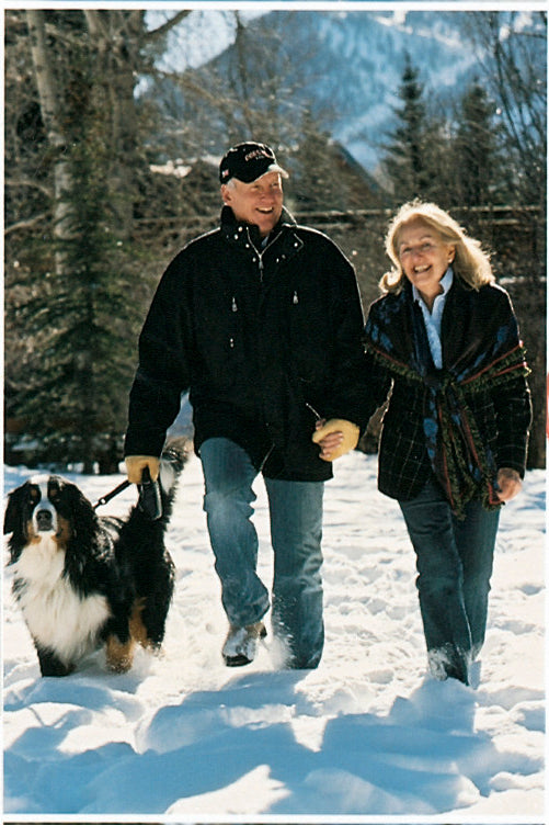 David and Renie Gorsuch walking a Bernese Mountain Dog in the snow with mountains in the background.