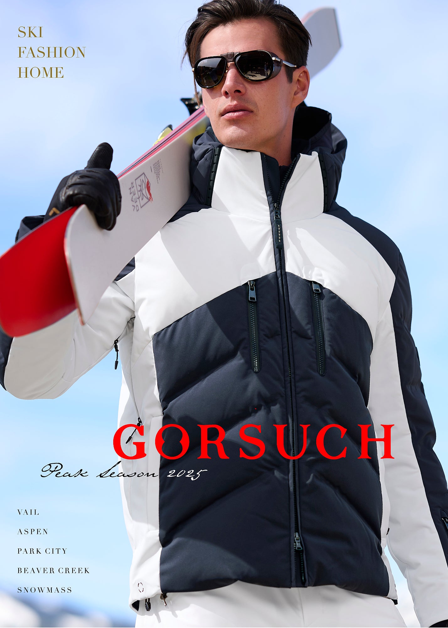 Man wearing navy and white Bogner Jervis Ski Jacket and sunglasses, holding skis against a clear blue sky.