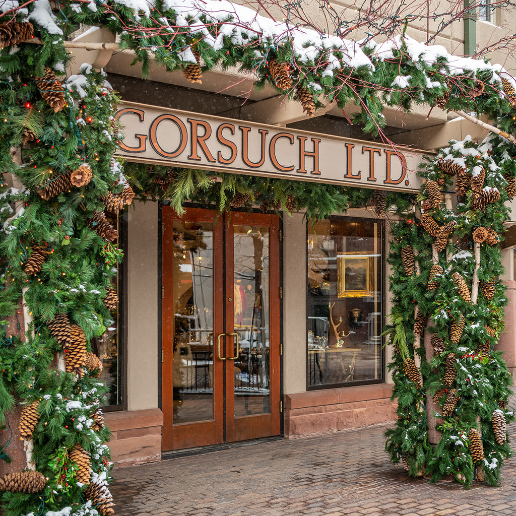 Decorated storefront with Christmas garlands and snow, featuring 'Gorsuch Ltd. in front of the Gorsuch Store in Aspen.