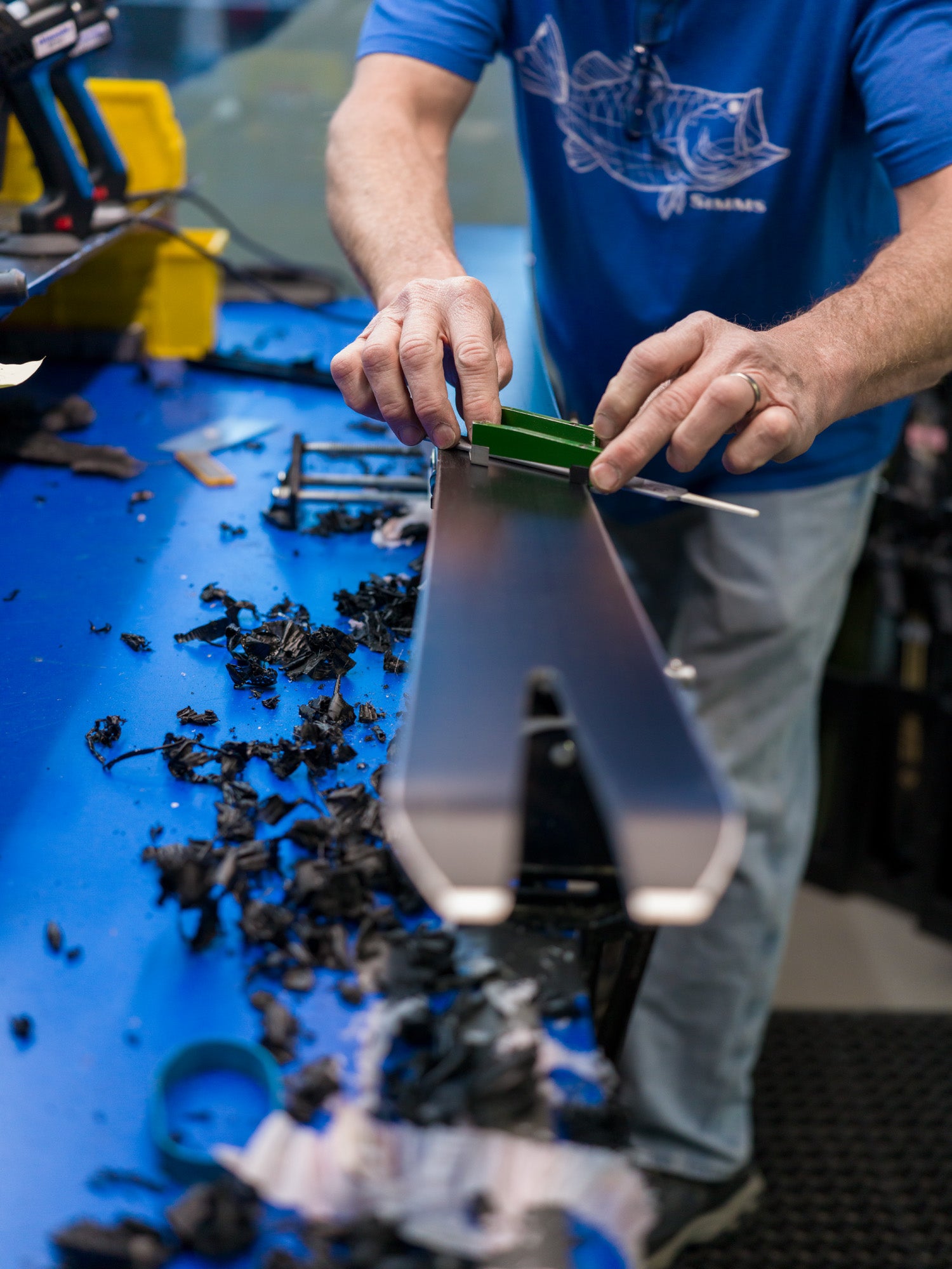 Man working on tuning the bottom of skis with tools on a blue workbench.