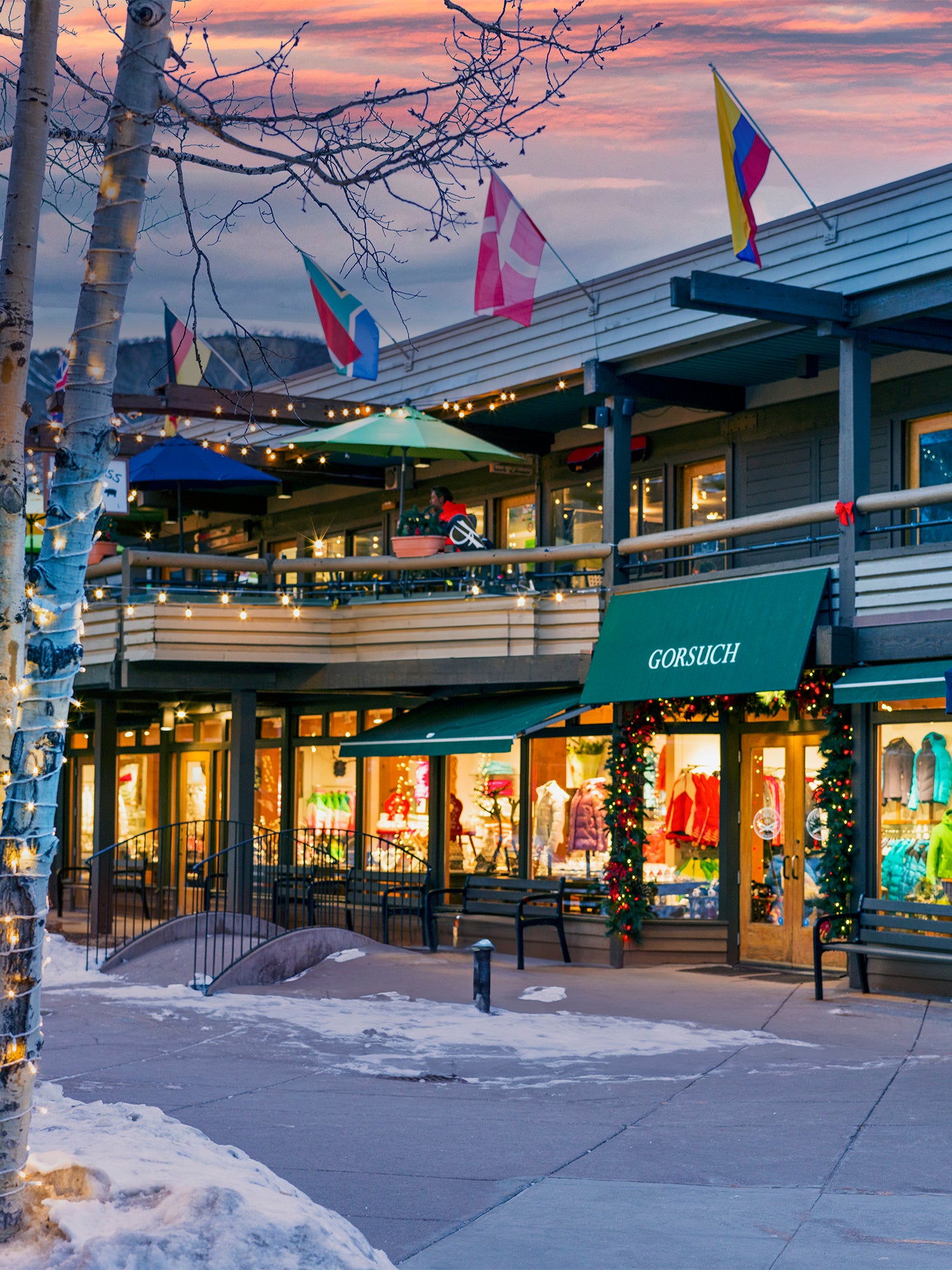 Outdoor shopping area with Gorsuch store at dusk, flags waving in the background.