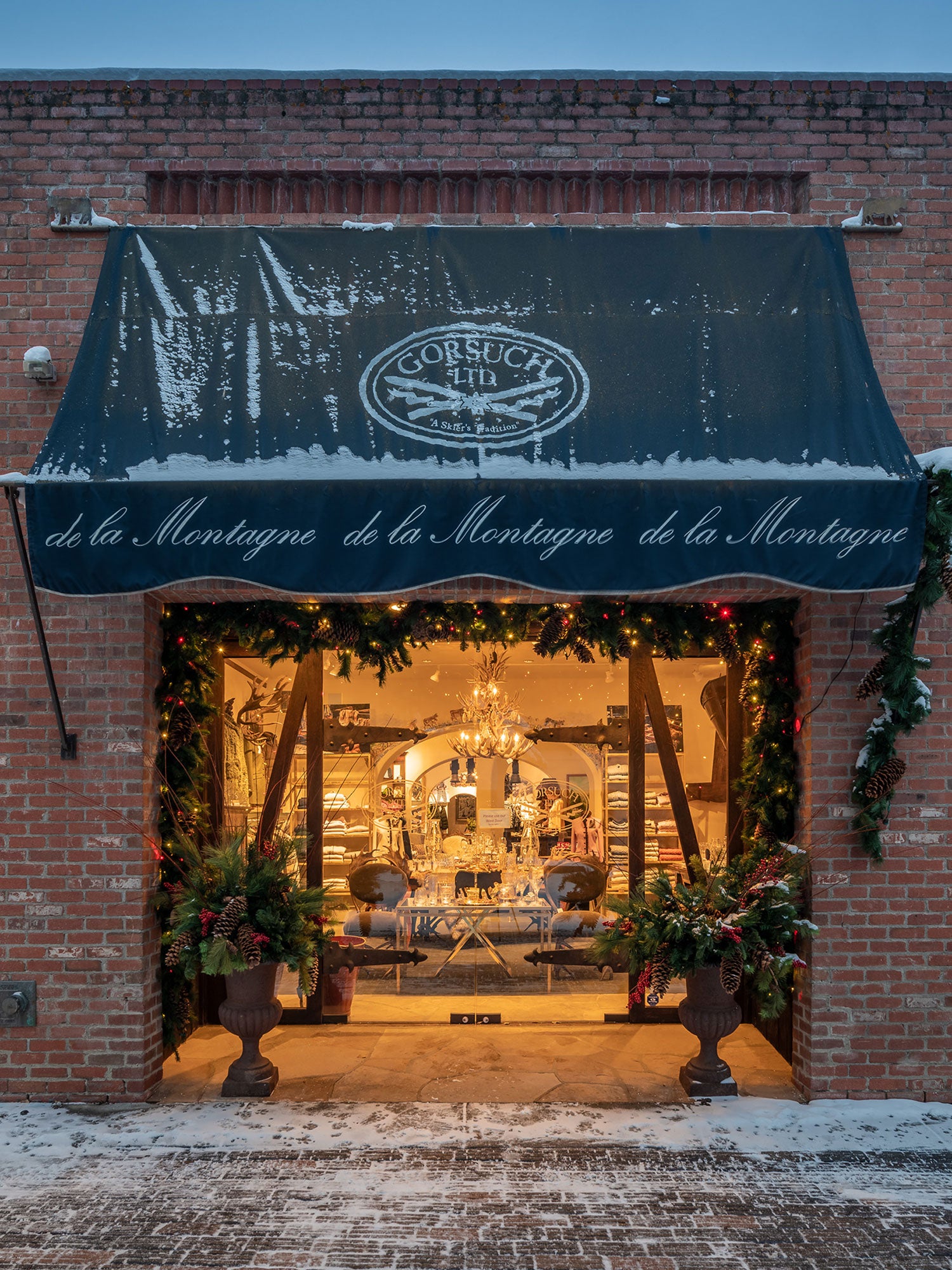 Snowy street scene with the front of the Gorsuch Store on Cooper Street in Aspen with festive Christmas decorations.