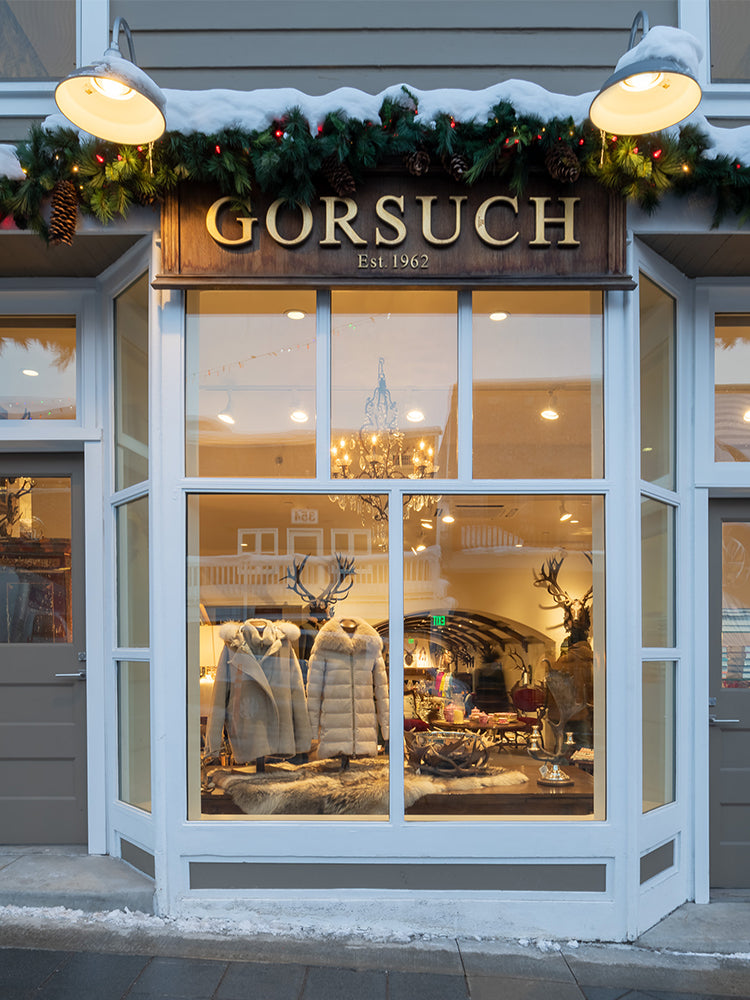 Gorsuch storefront in Park city with Gold and wood Gorsuch sign decorated with pinecones and garland above the sign.