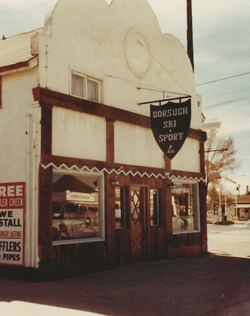 Vintage photo of one of the first Gorsuch stores, white with wood trim and Gorsuch Ski & Sport sign hanging outside.