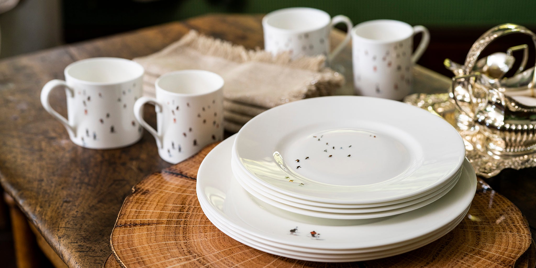 White ceramic skier dinnerware set by Dede Johnston on a wooden table.