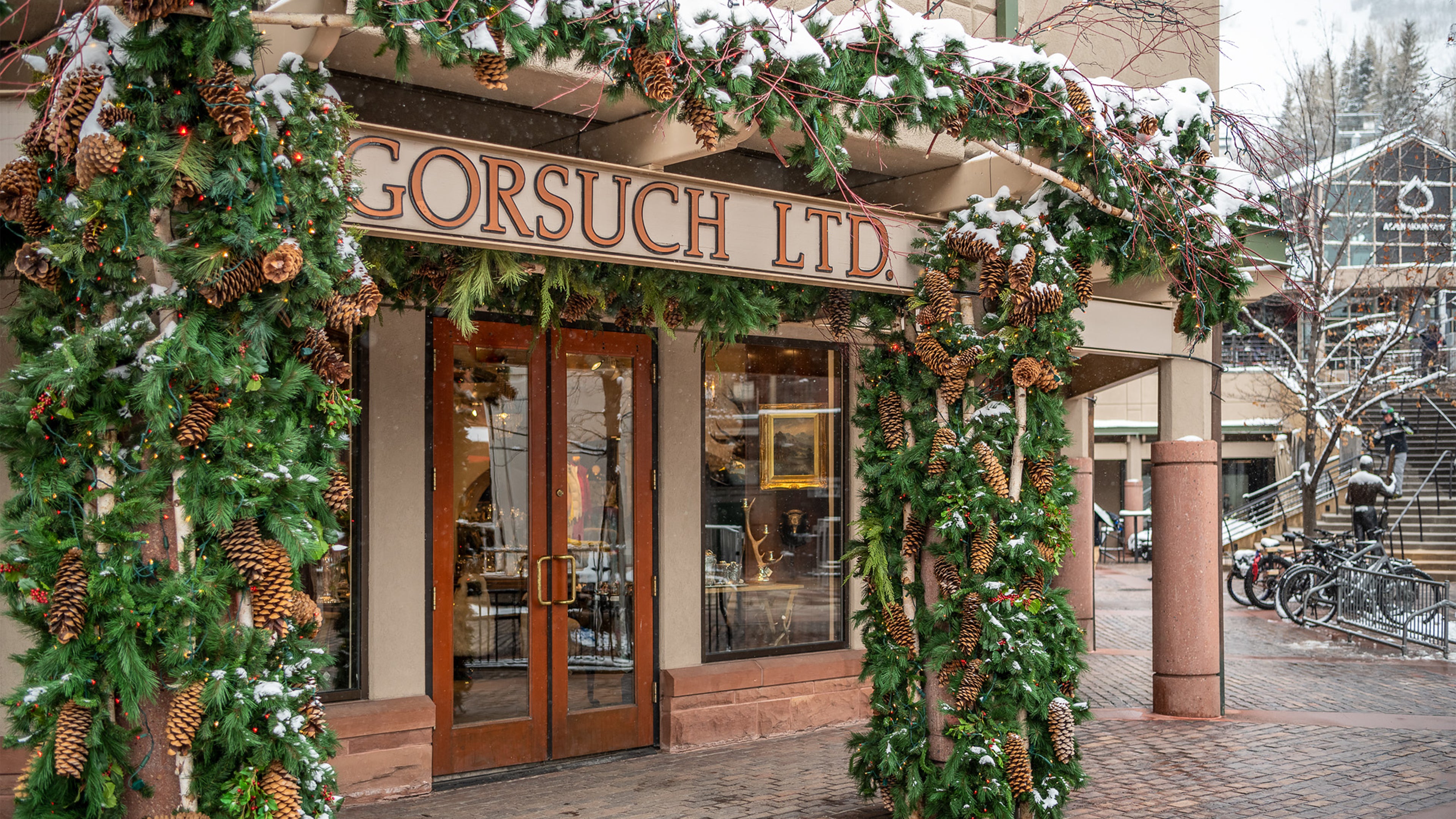 Decorated storefront with Christmas garlands and snow, featuring 'Gorsuch Ltd. in front of the Gorsuch Store in Aspen.