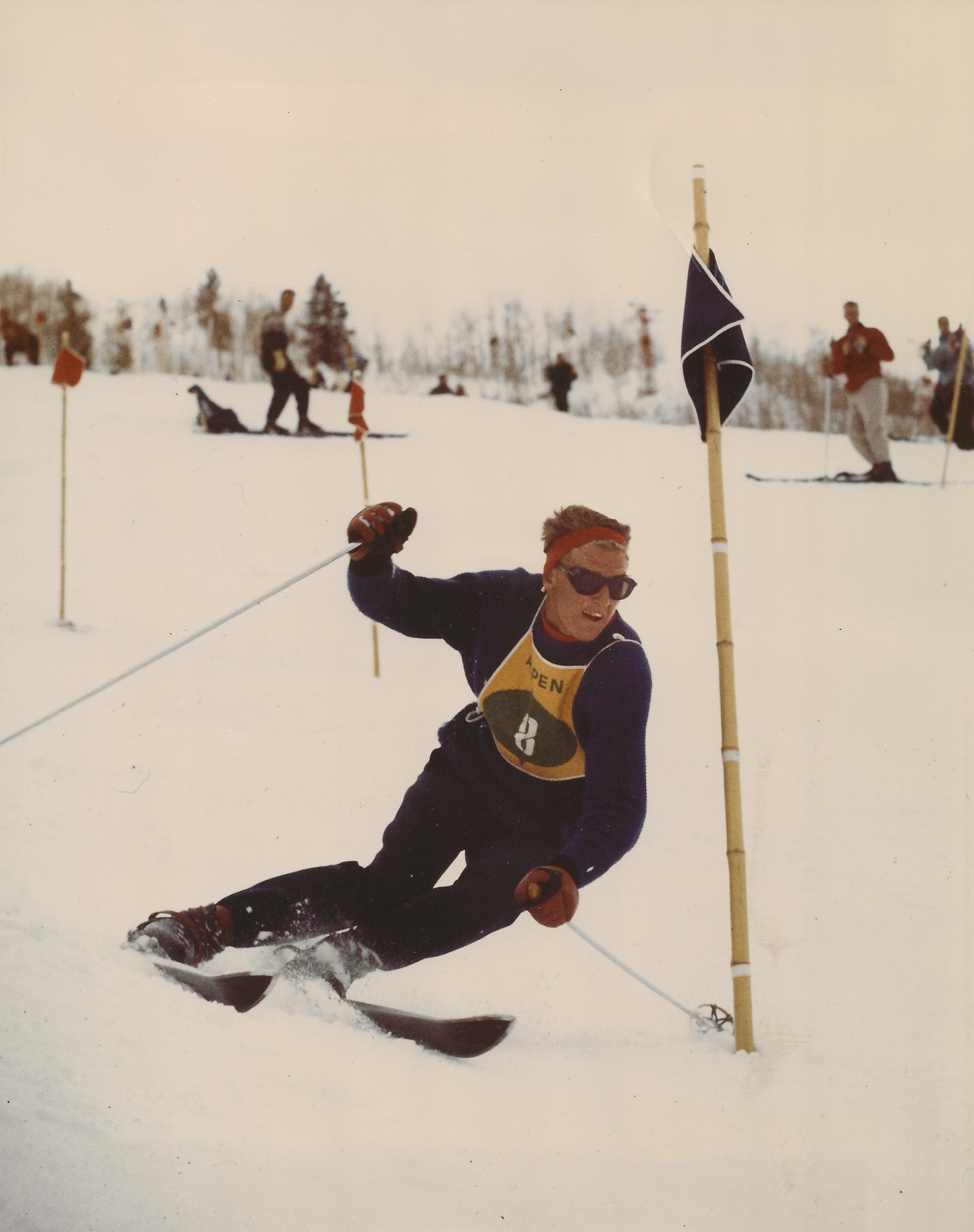 David Gorsuch skiing in a competitive event with flags and other skiers in the background.