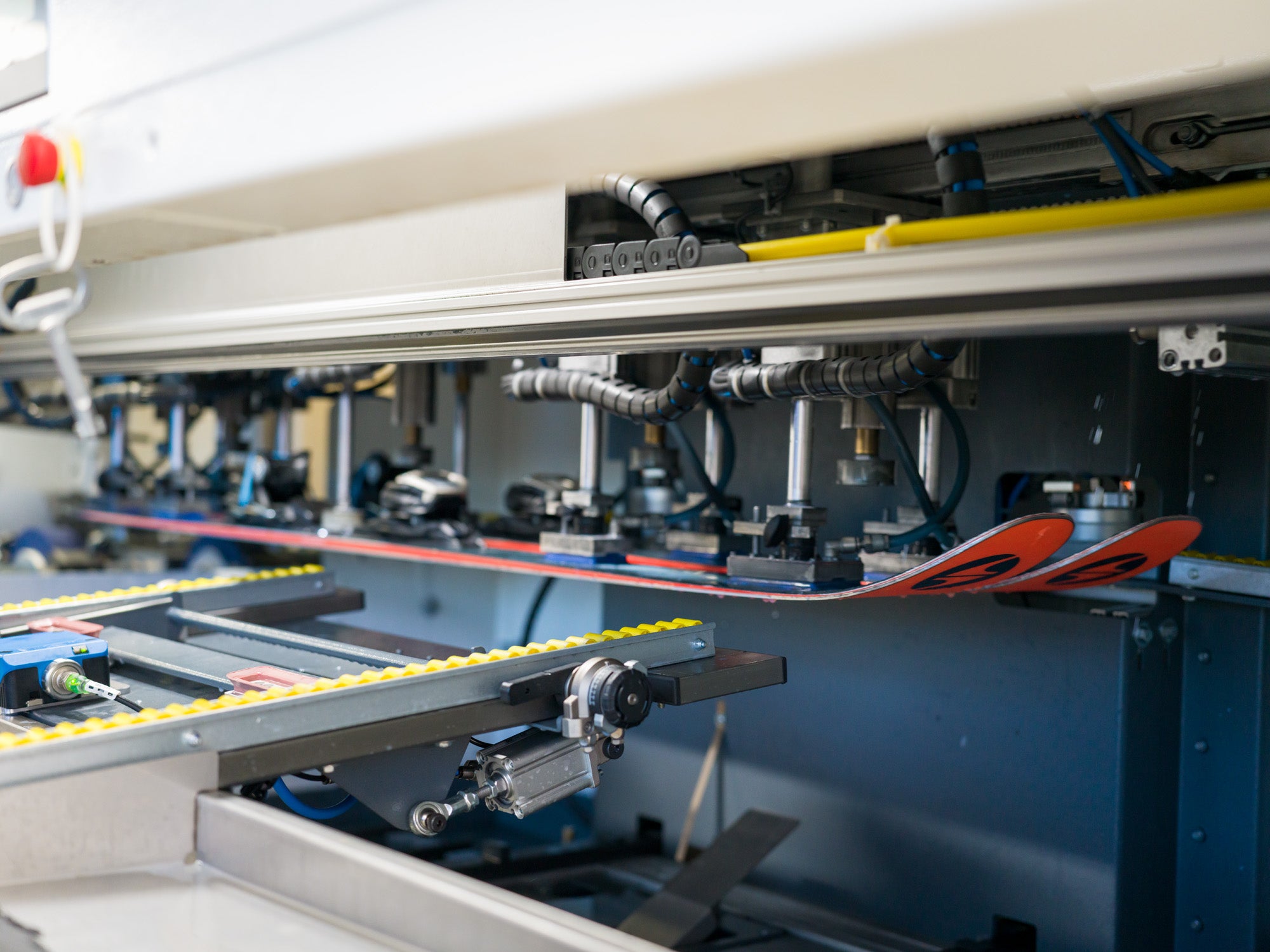 Skis being processed on a ski manufacturing machine in a workshop.