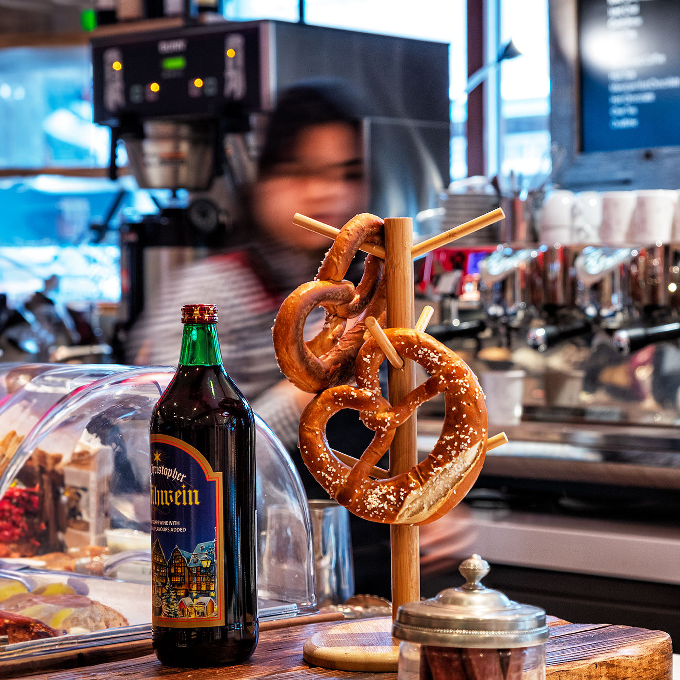 Bottle of beer with pretzels on a stand in a coffee shop setting.