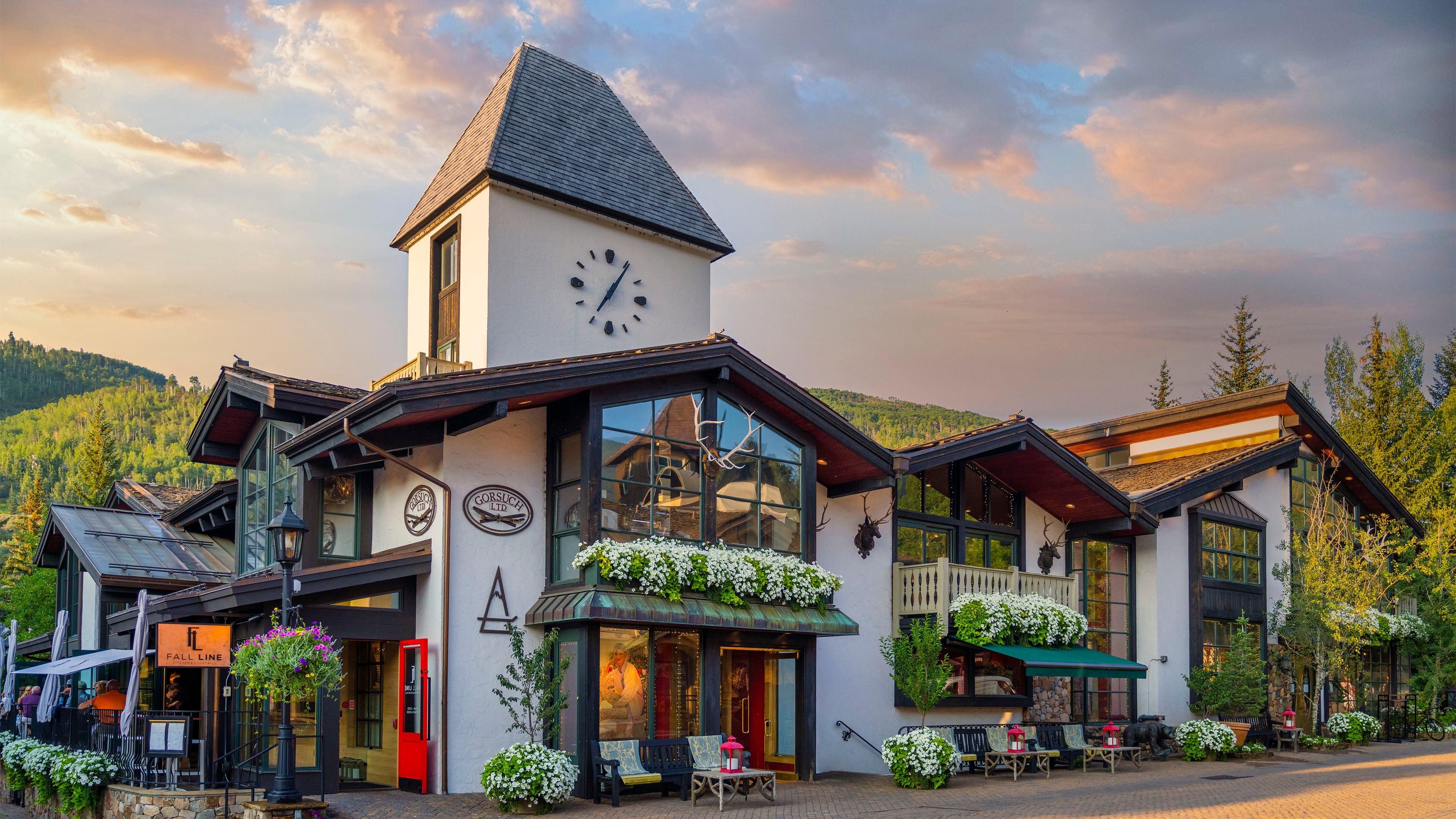 Gorsuch store in Vail Village featuring the iconic clock tower with mountains and trees.