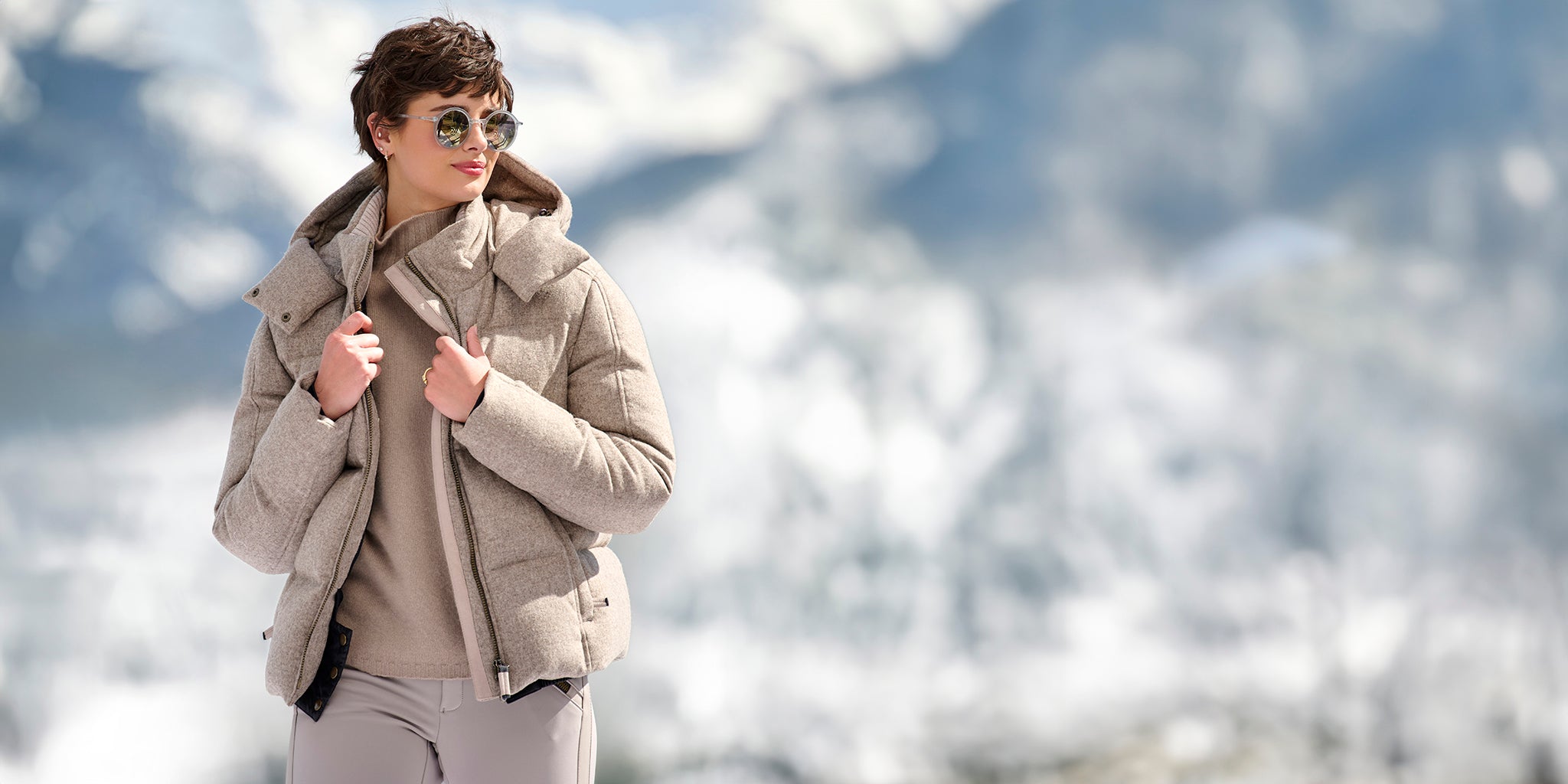 Woman wearing the Isabel Loden Ski Jacket in cashmere color by Frauenschuh, standing against a snowy mountain background.
