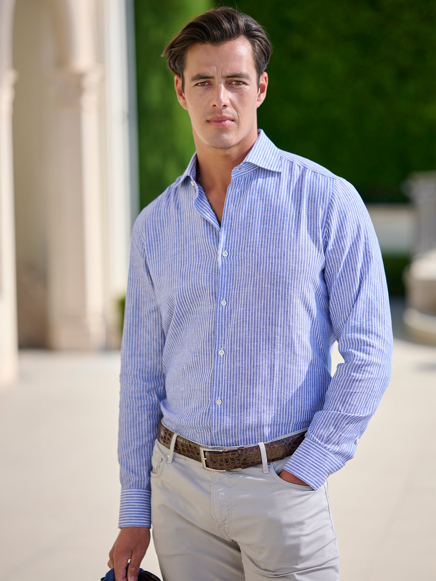 Man wearing a blue striped shirt and light pants outdoors